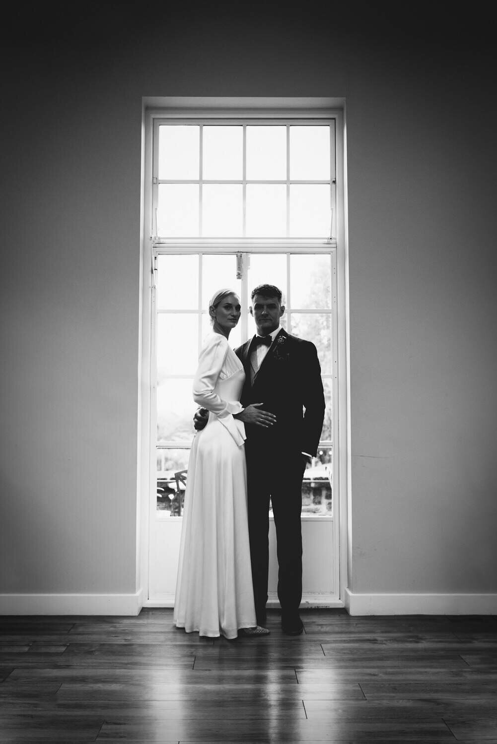 Bride and Groom stand at large Window