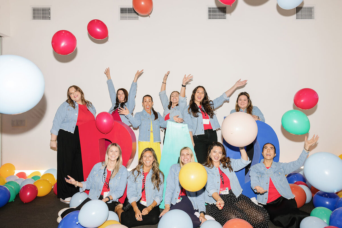 The Intertwined team cheering and throwing balloons for a team photo for RAD Camp.