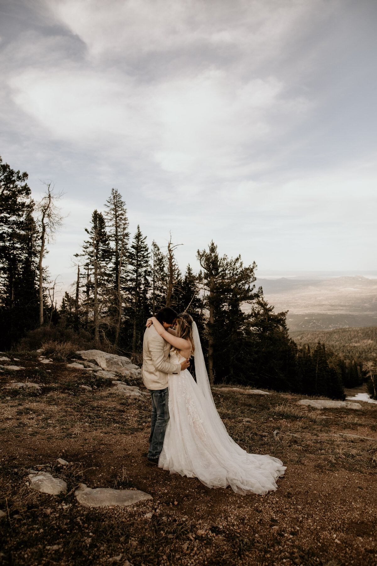 bride and groom about to kiss on top of a mountain