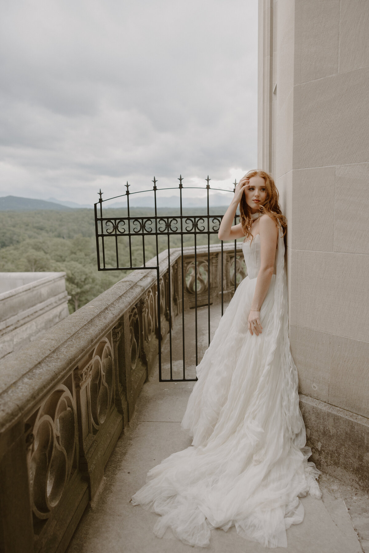 Bride standing beside ornate iron gates at the Biltmore, light softly highlighting her gown and veil.