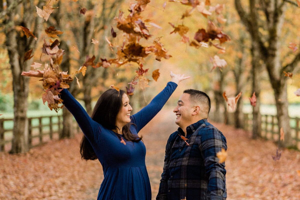 Bride and groom throwing fall leaves at Rockwood Farm, one of the best places for engagement photos in Seattle during autumn.