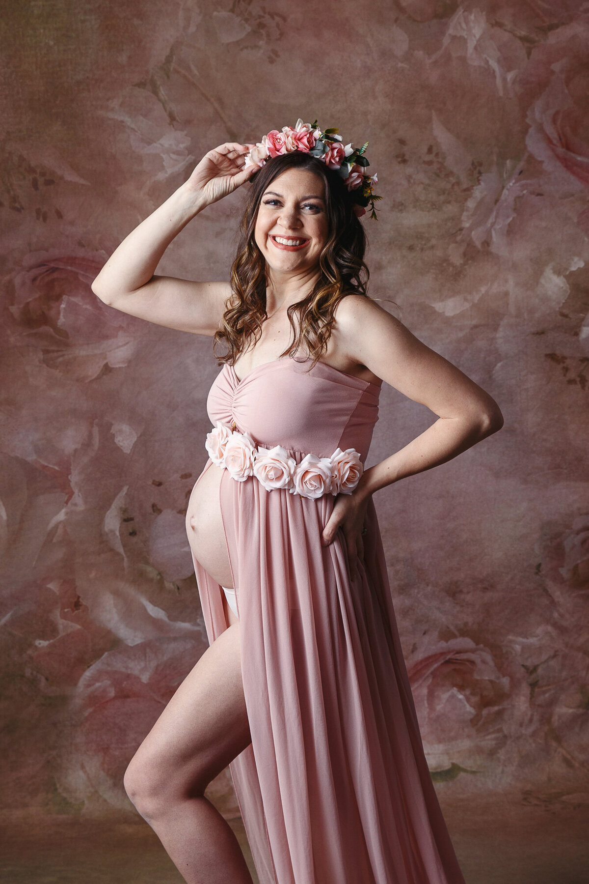 Pretty pregnant woman wearing a pink gown and flowered crown