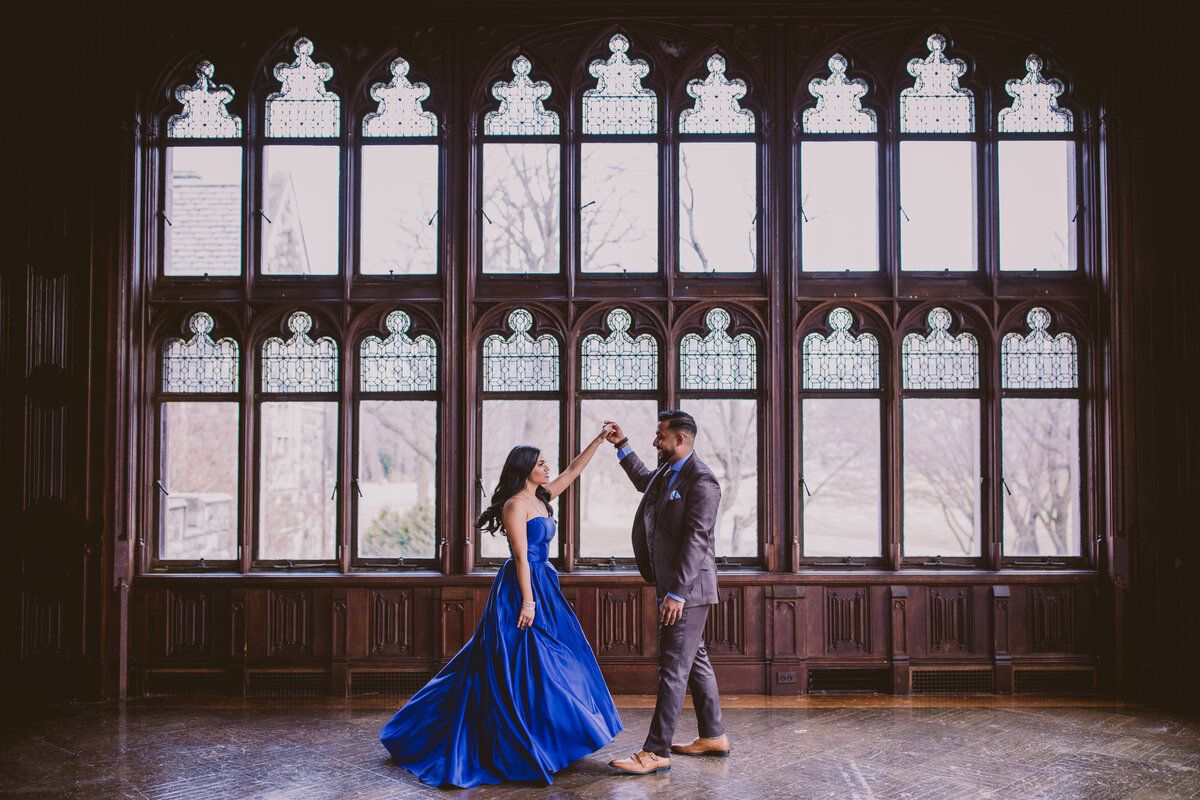 Groom twirls bride in blue formal clothing in an old vintage room at the hempstead house at sands point preserve