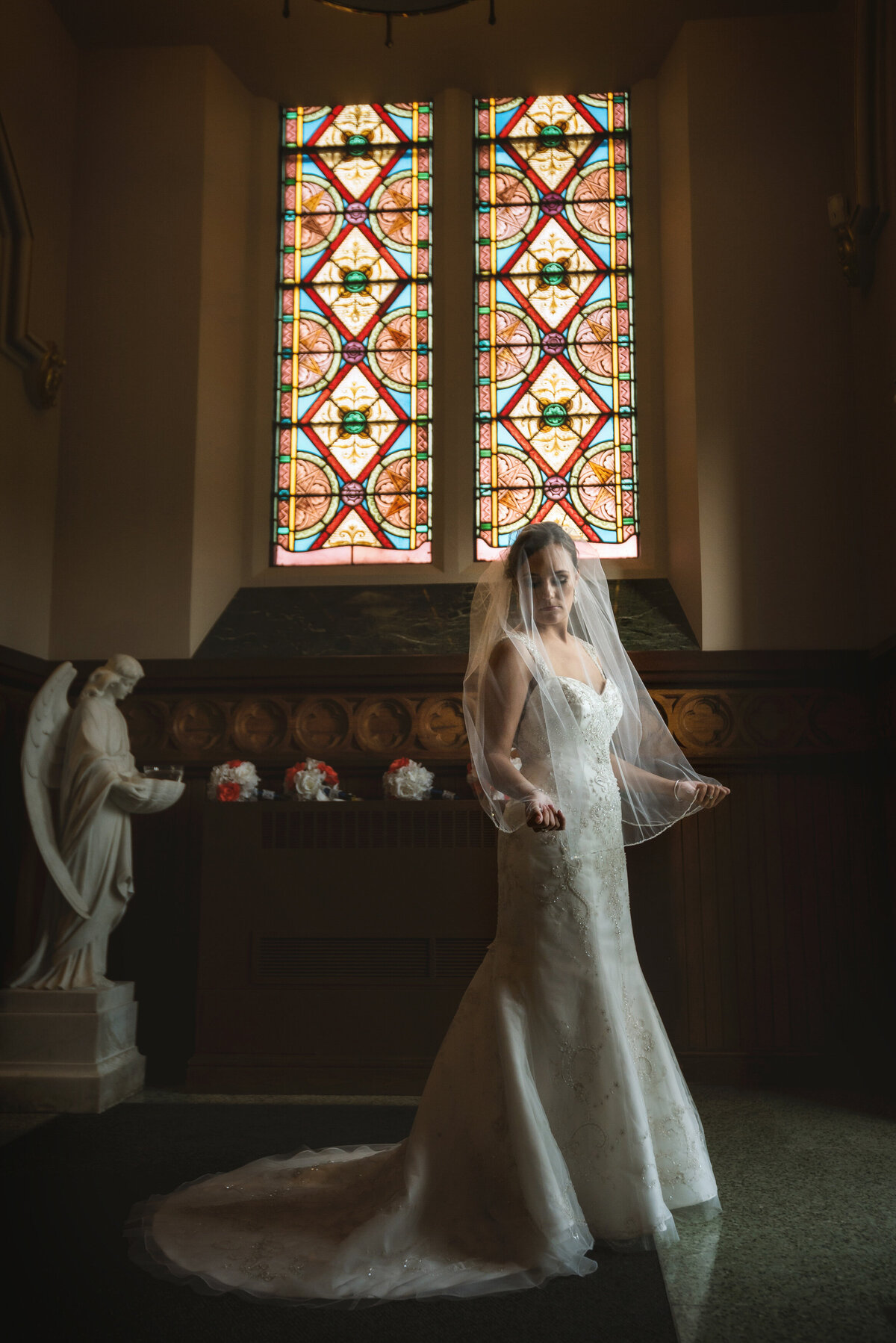 Bride holding veil in front of window at Saint Peters Cathedral in Erie Pennsylvania.