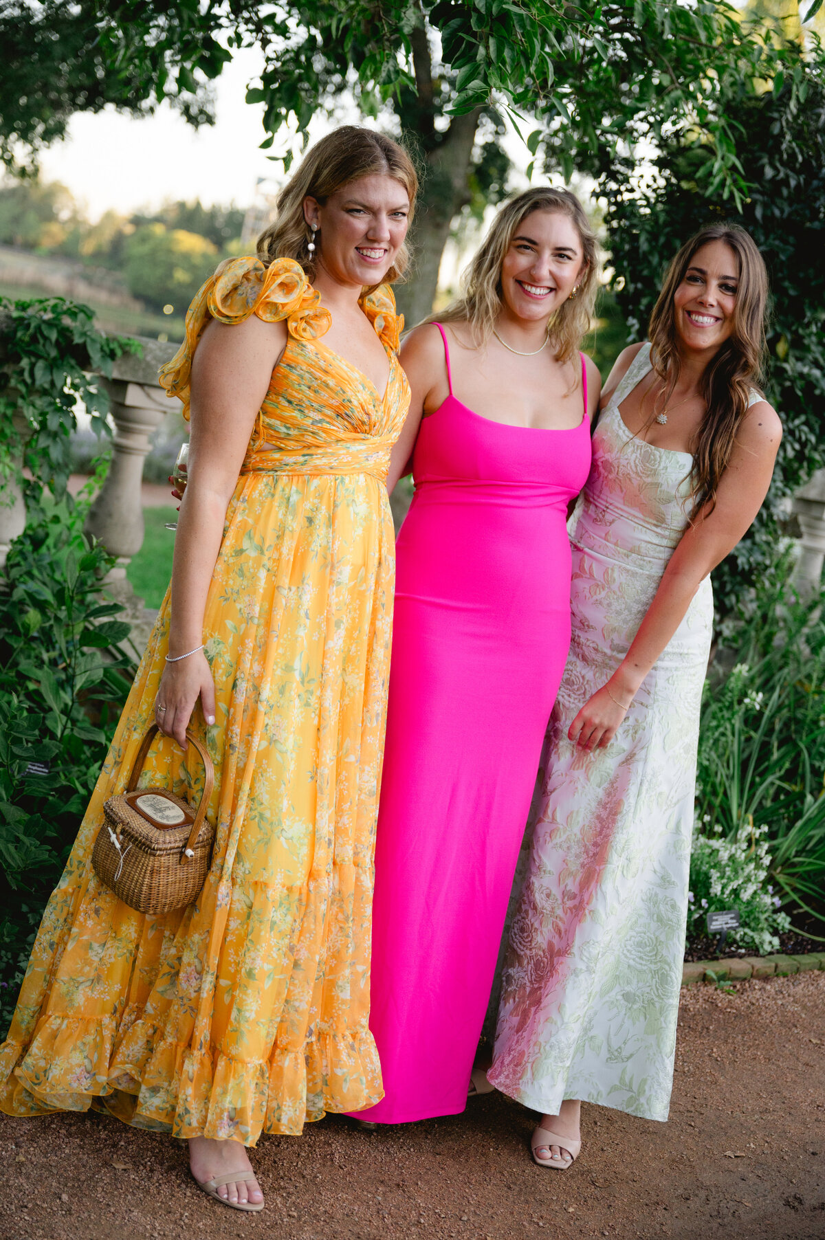Three women in colorful dresses smiling at a wedding at the Chicago Botanic Gardens.