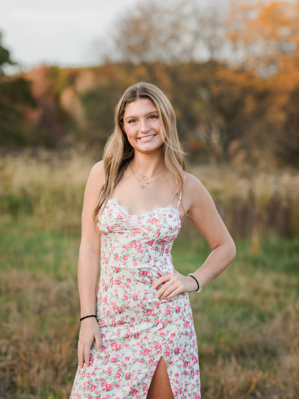 senior girl in floral dress posing for senior photos in field cleveland senior phototgrapher