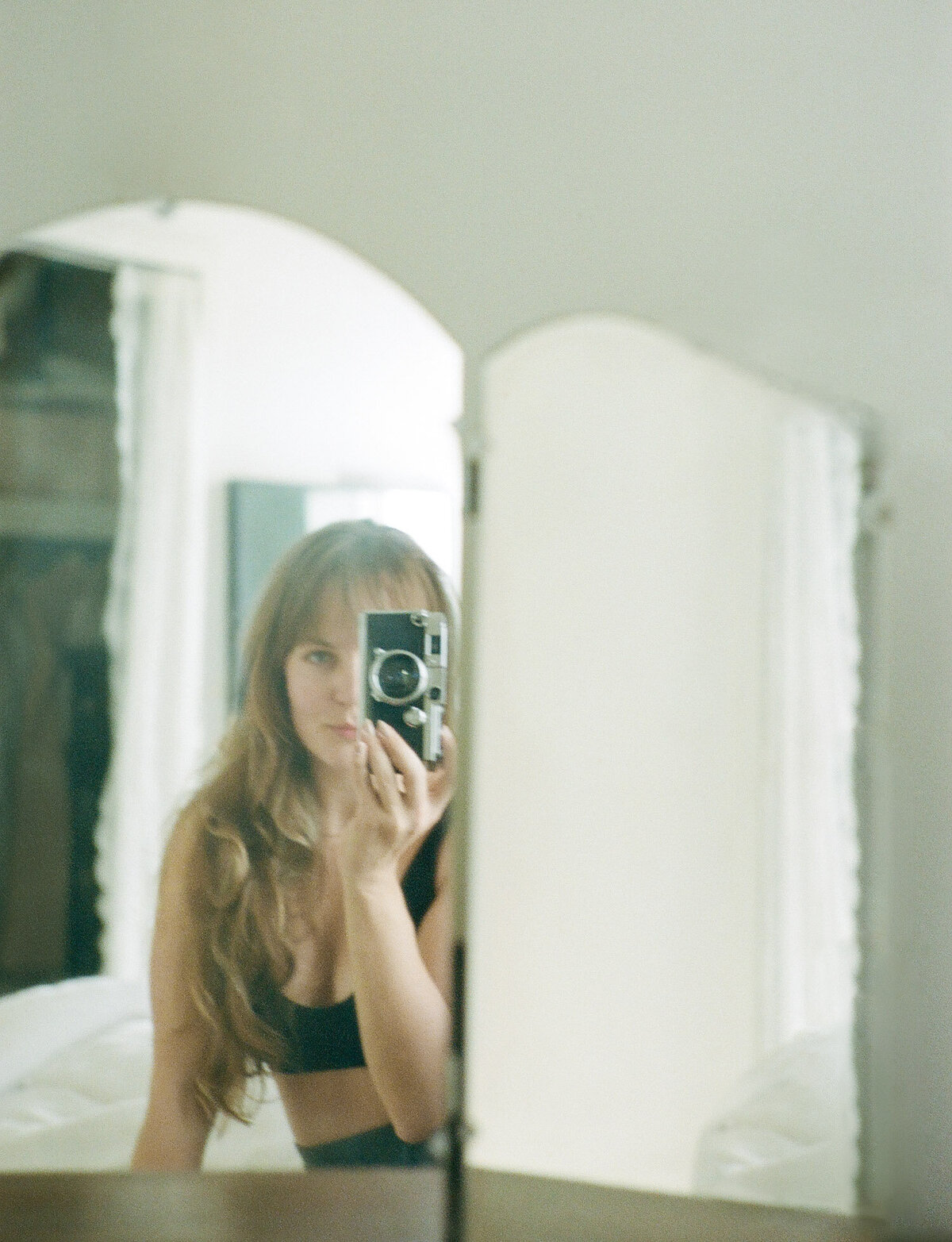 soft film self portrait of female photographer in vanity mirror, vintage rangefinder camera