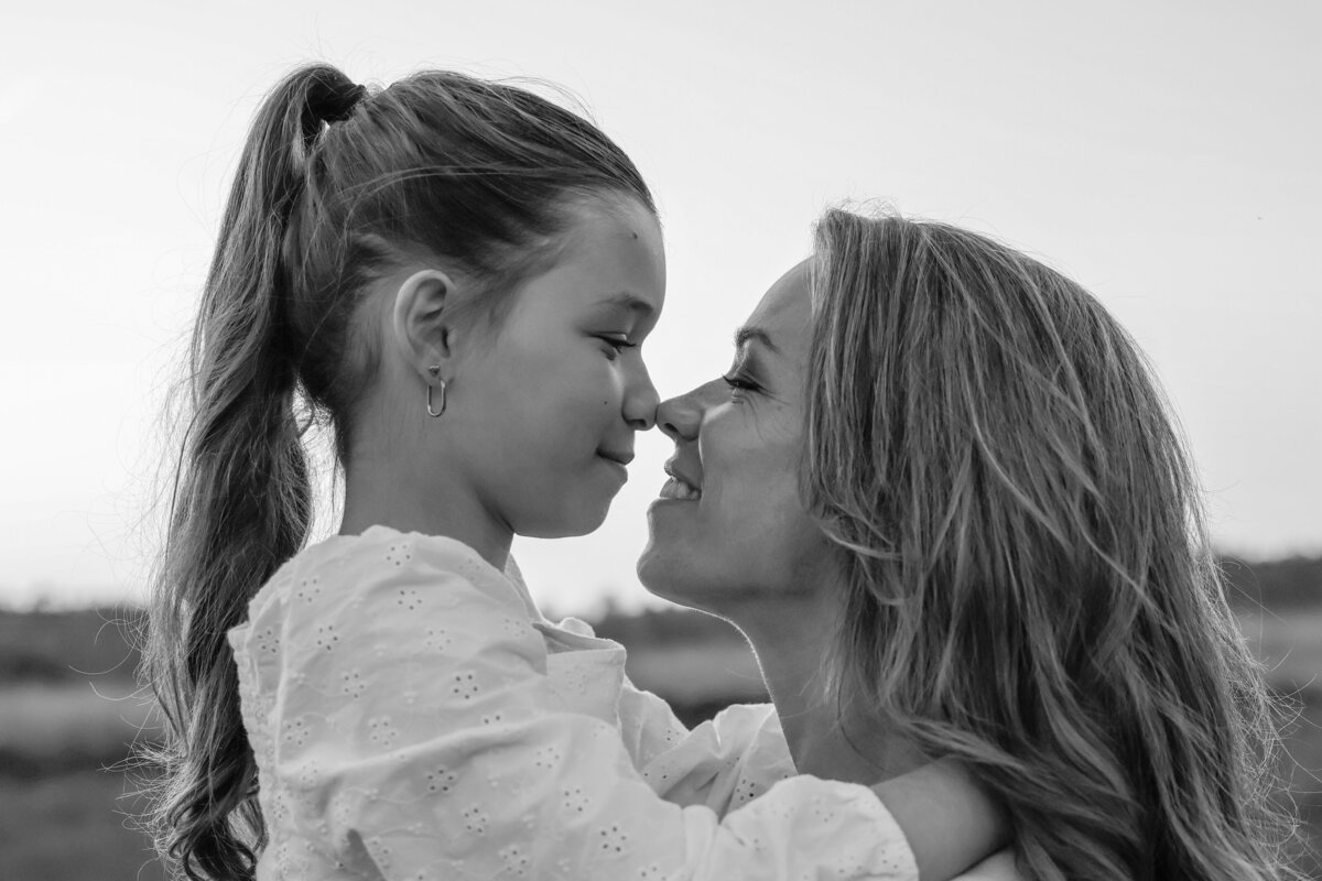 Zwart wit foto van moeder en dochter die liefdevol hun neuzen tegen elkaar hebben.