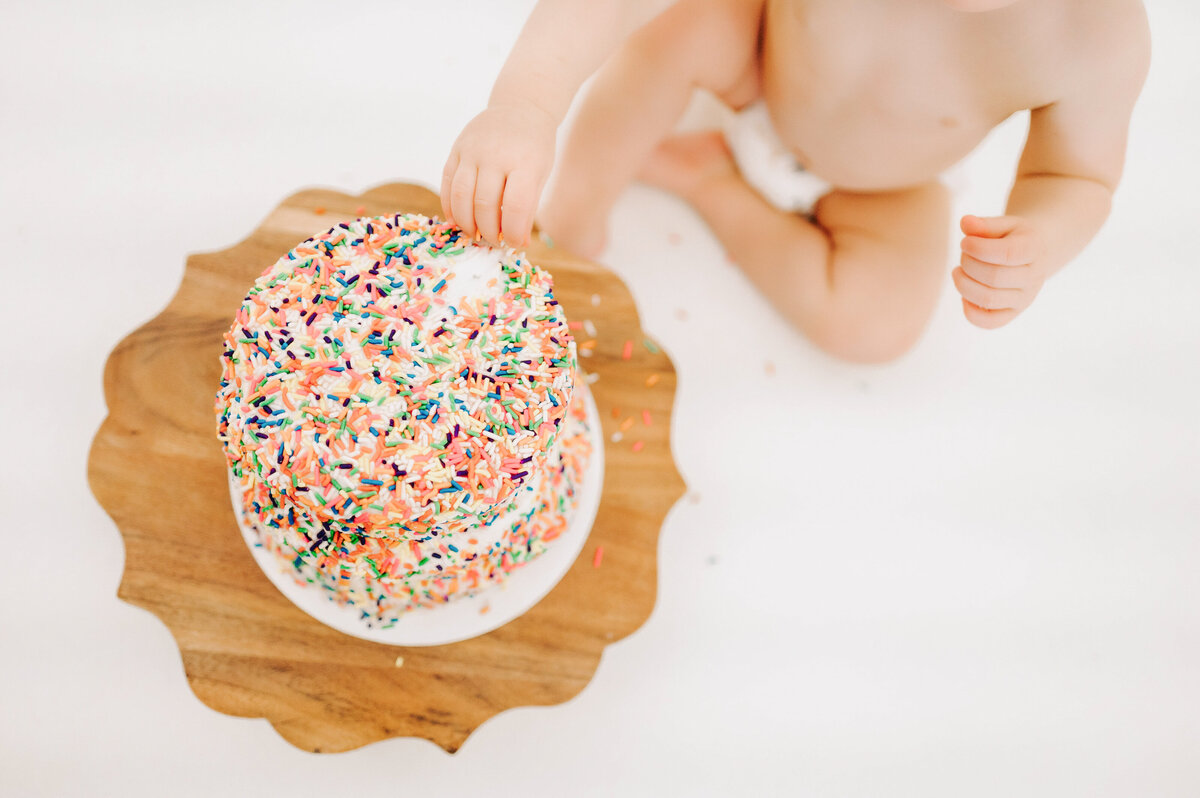 close up of baby eating cake with his hands in Springfield MO kids photography studio