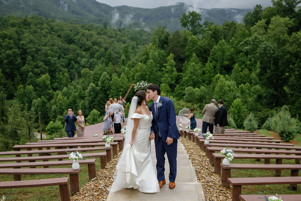 bride and groom exit their elopement ceremony and kiss at the end of the aisle at Mountain Mist wedding venue while they elope to Gatlinburg 