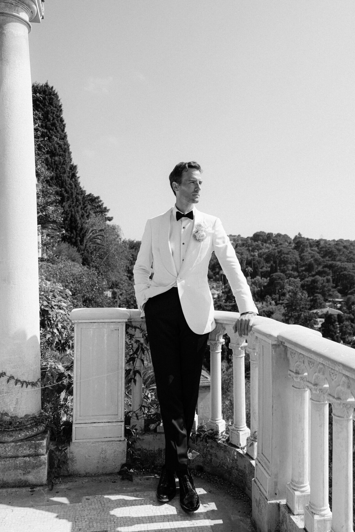 Black and white image of the groom posing at a balcony of VIlla Ephrussi.
