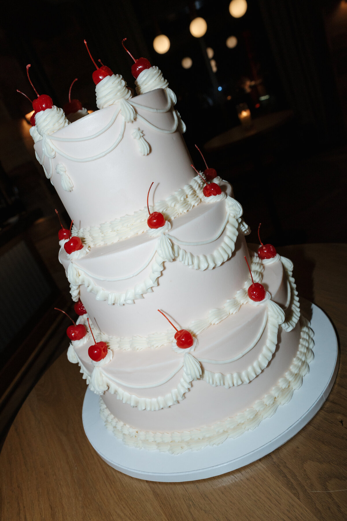 A beautiful 3 tier cake with cherries on top.