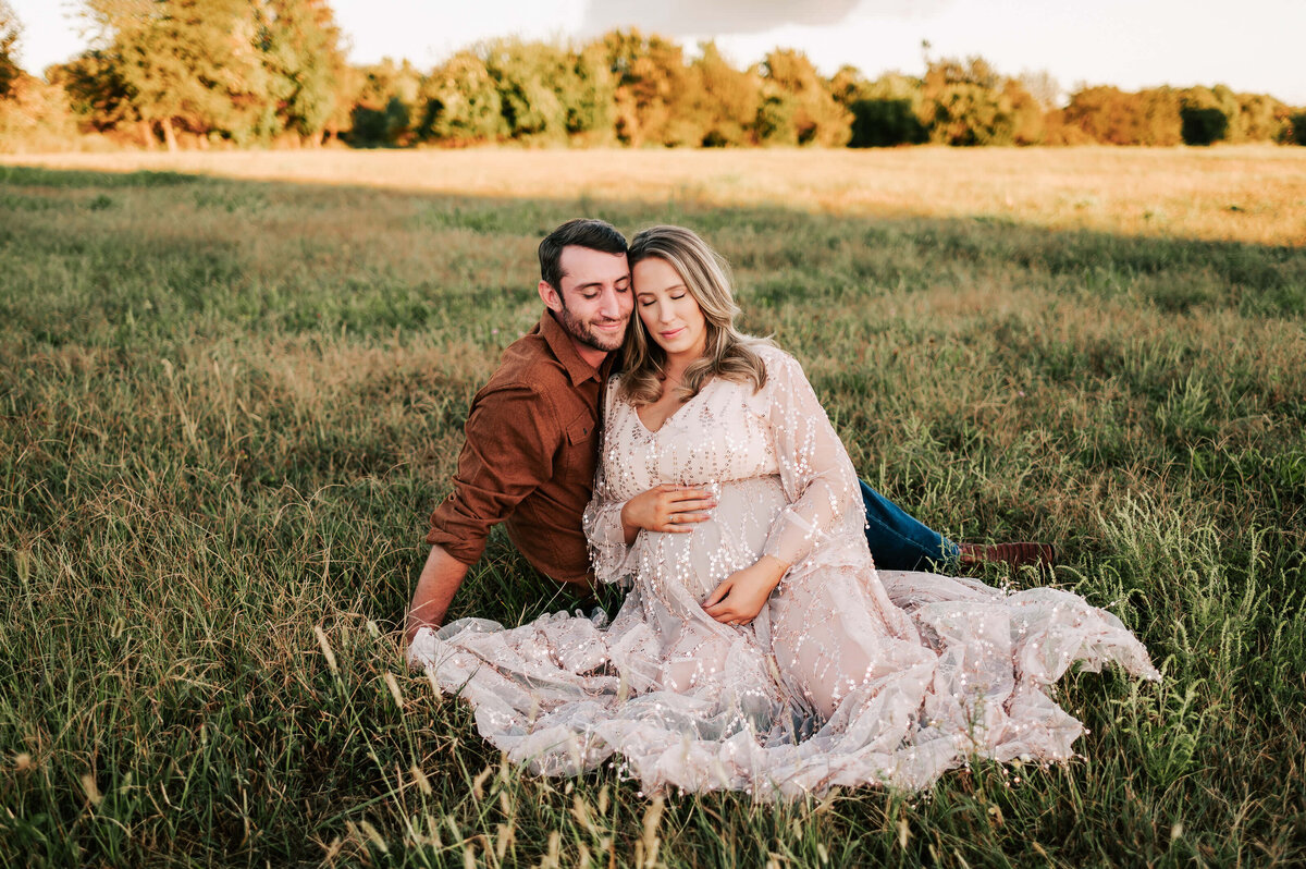 pregnant couple cuddling in a field during maternity pictures in Springfield MO