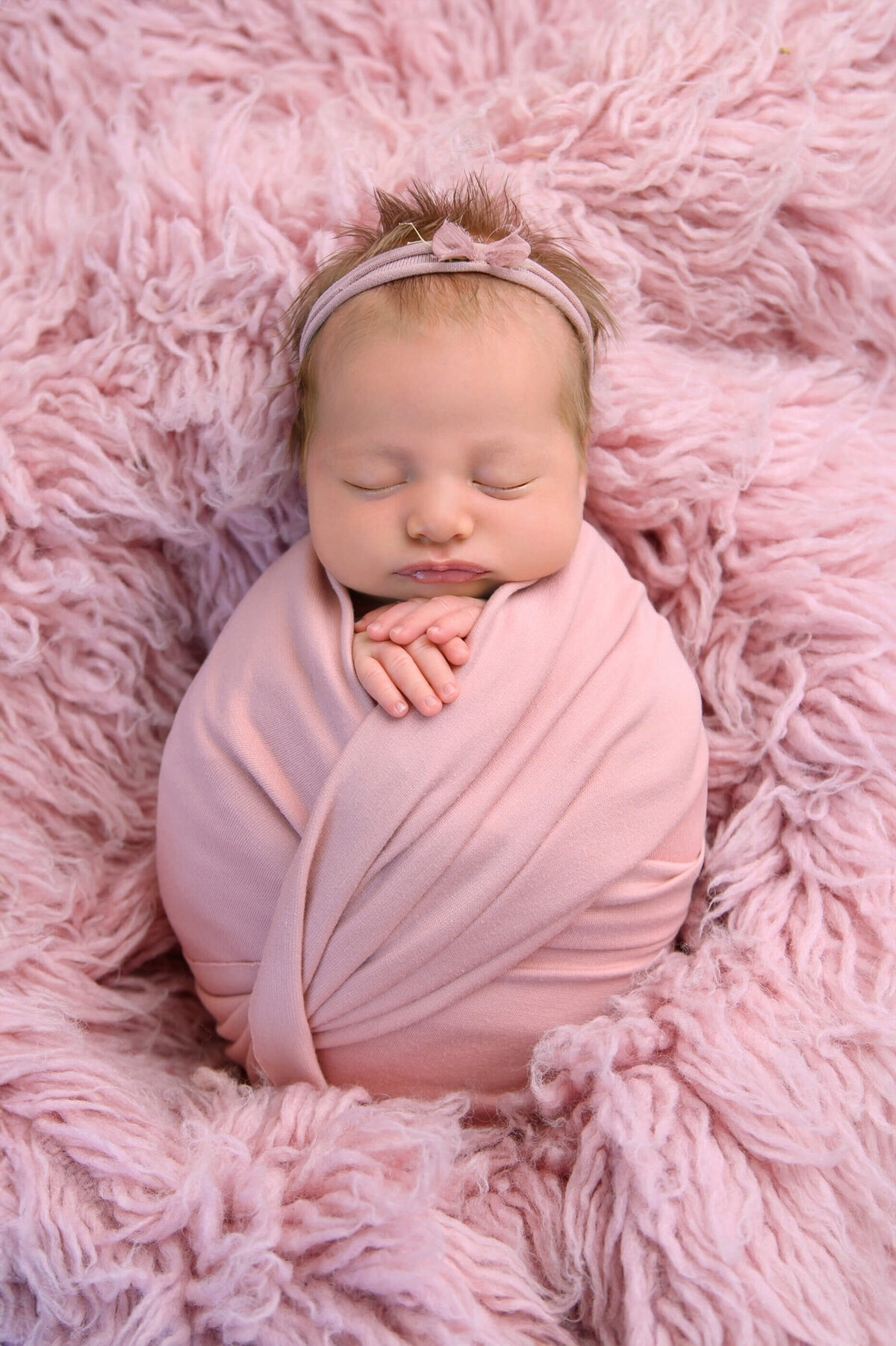 newborn girl wrapped in pink for her newborn photos in Burlington