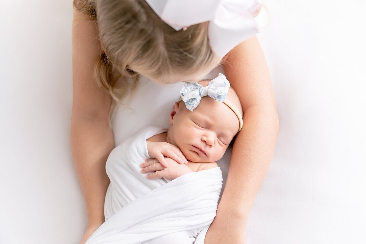 Big sister cuddling newborn during newborn photography session in Savannah GA
