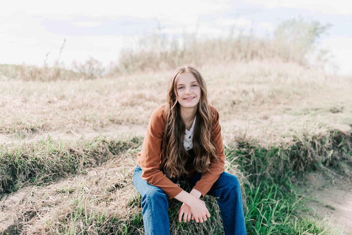A young lady sitting on a rock. 