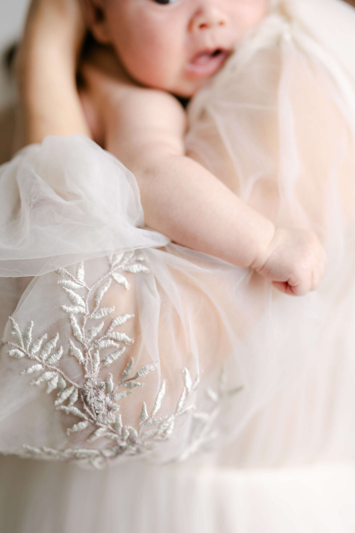 Mother cradling newborn in arms during intimate Bay Area newborn photography session.