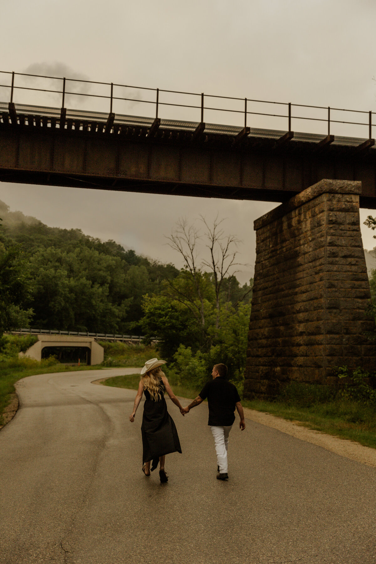 Couple holding hands and walking under a bridge for engagement photos 