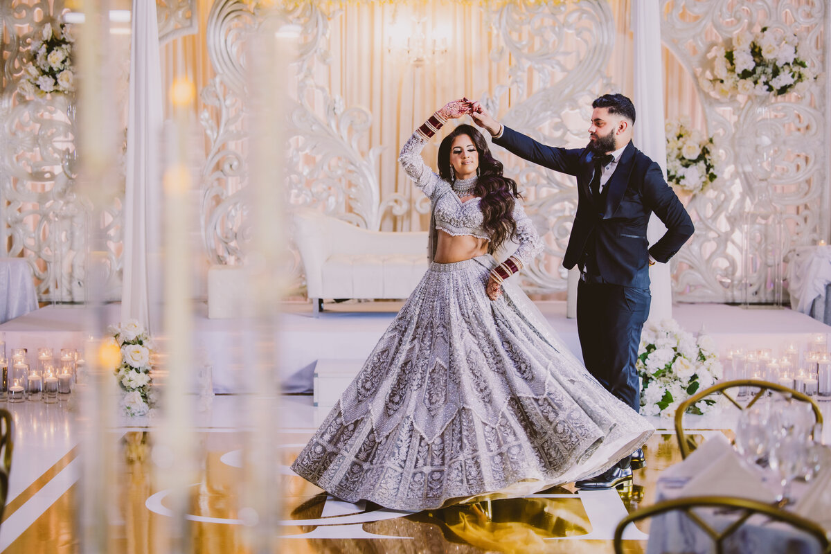 Groom twirling her bride at their Sikh Indian wedding reception ballroom at Crest Hollow Country Club in New York