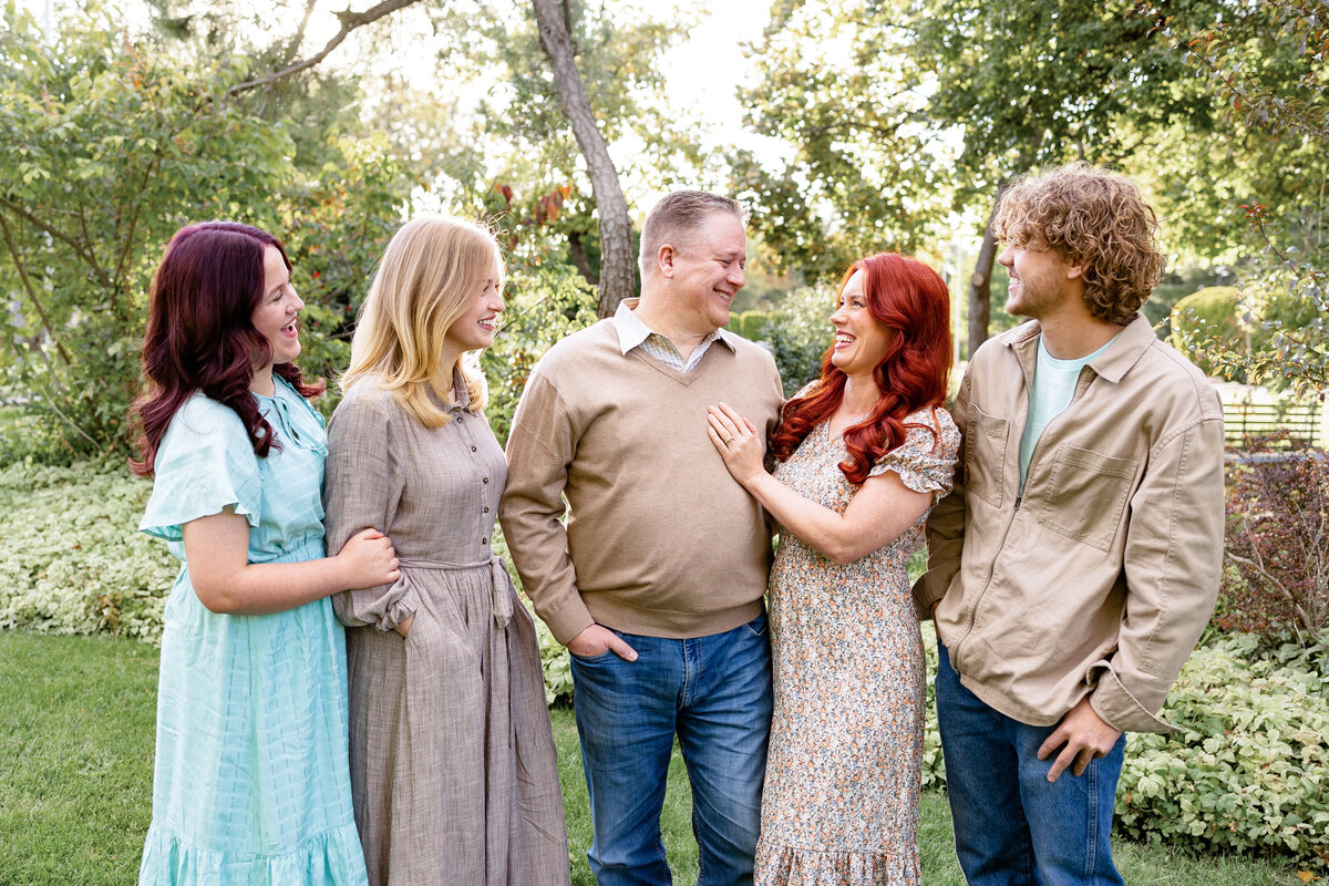 Parents and their three children share a laugh together in a scenic outdoor setting, surrounded by trees and greenery. at the Internation Peace gardens in Salt Lake City.
