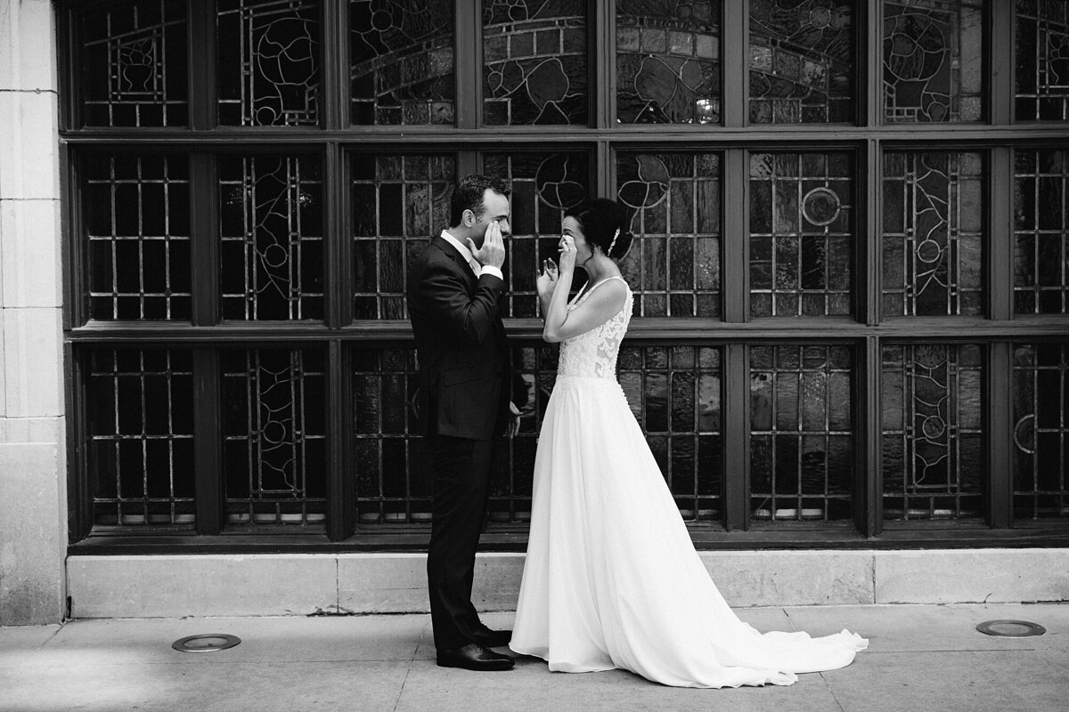 Black and white image of couple crying during first look