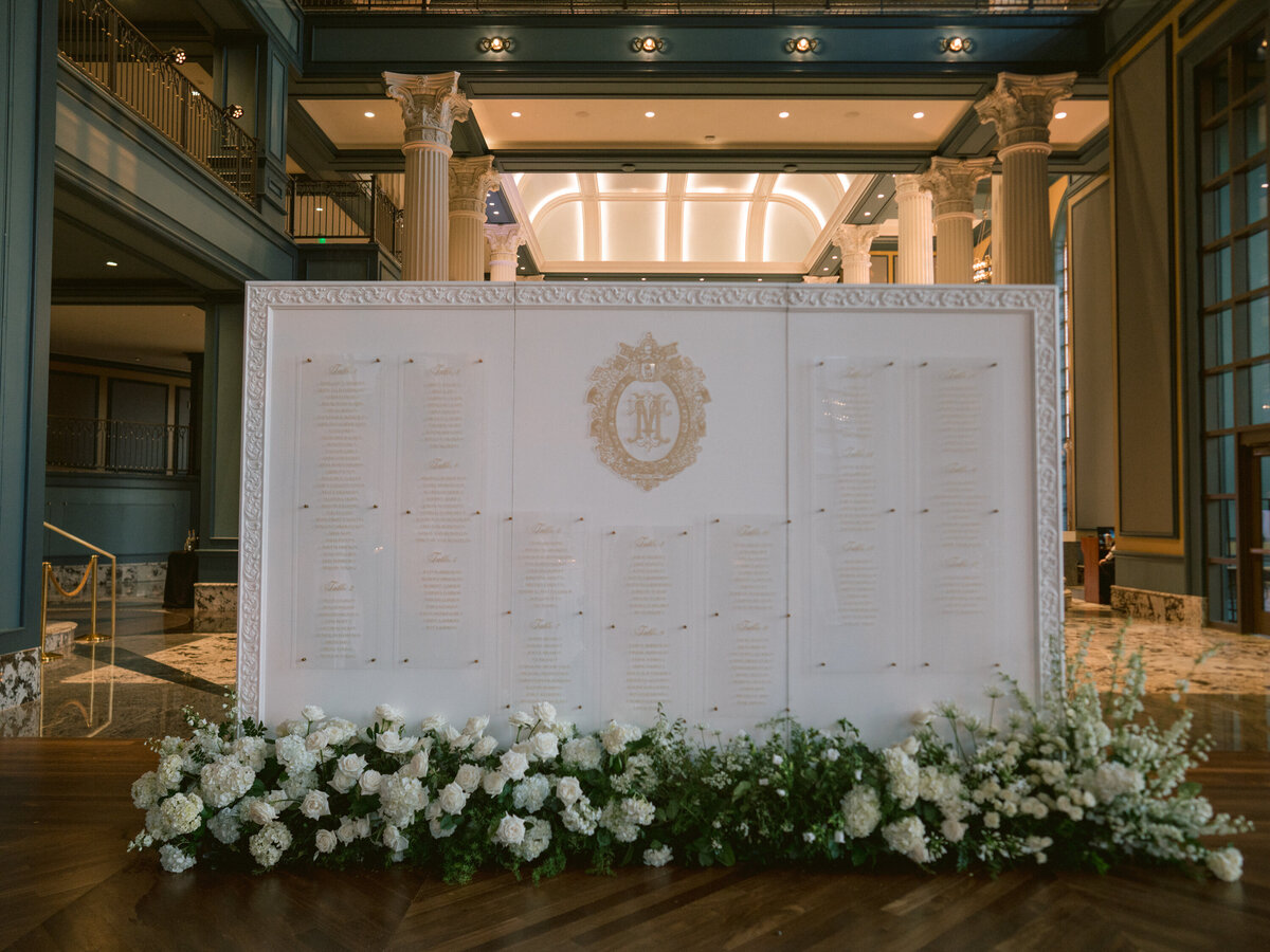 Gold wedding crest and table numbers on escort card wall at high end wedding in Nashville, TN