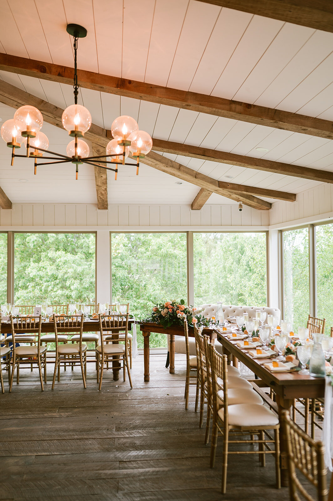 golden chivari chairs and wood farmers tables set with beautiful china and glassware for a reception at Willowbrook Wedding venue