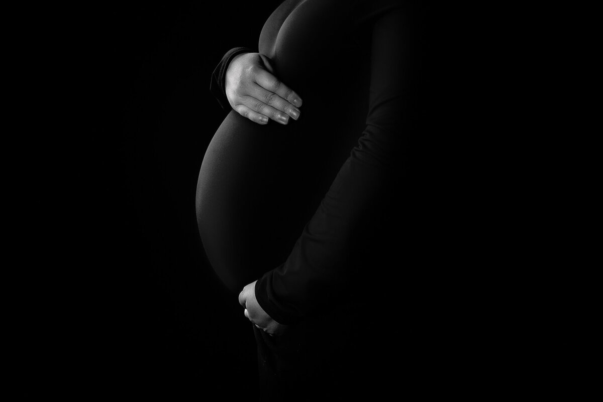 Dramatic black-and-white silhouette maternity portrait, highlighting the beauty of pregnancy. Captured in Overland Park, Kansas, for families seeking artistic maternity photography.
