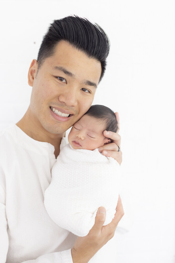 dad holding newborn baby boy in studio portrait session