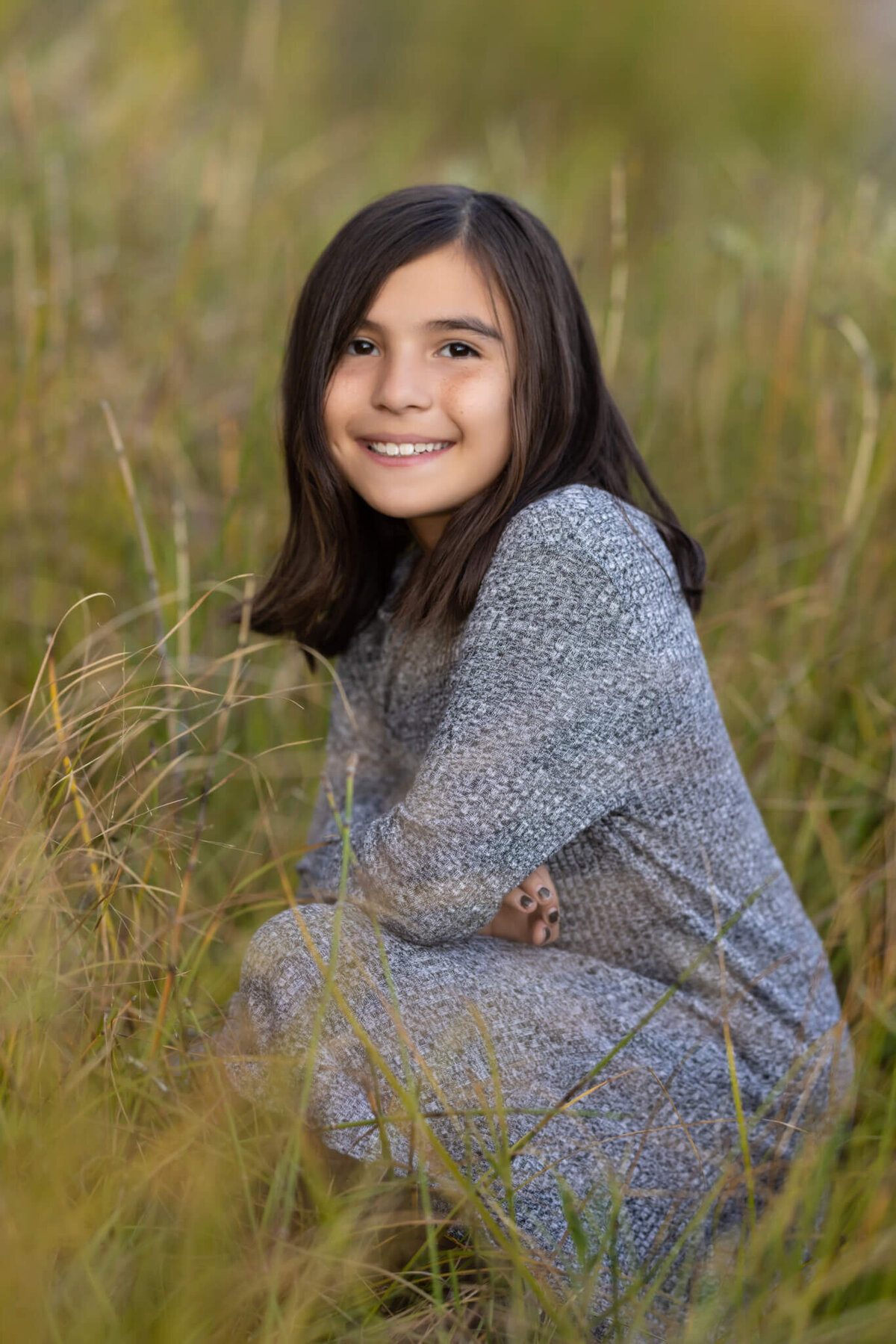 a young girl kneeling in tall grass