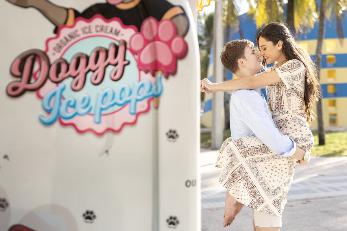 Engagement portrait of a couple embracing in front of a Doggy Ice Pops truck in Miami, Florida, captured by Rodrigo Varela Photography. Playful and candid moment reflecting the couple's joyful personalities.