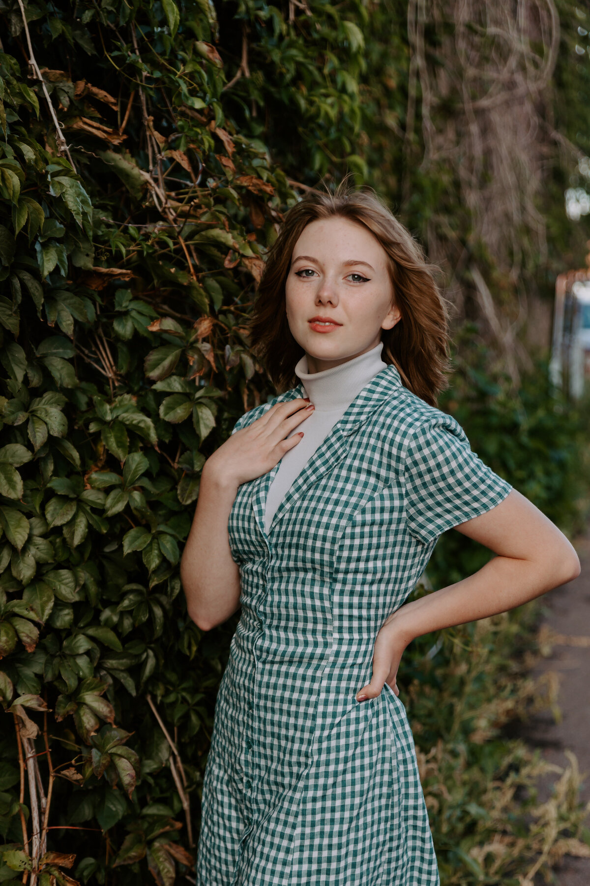 A person standing along green vines