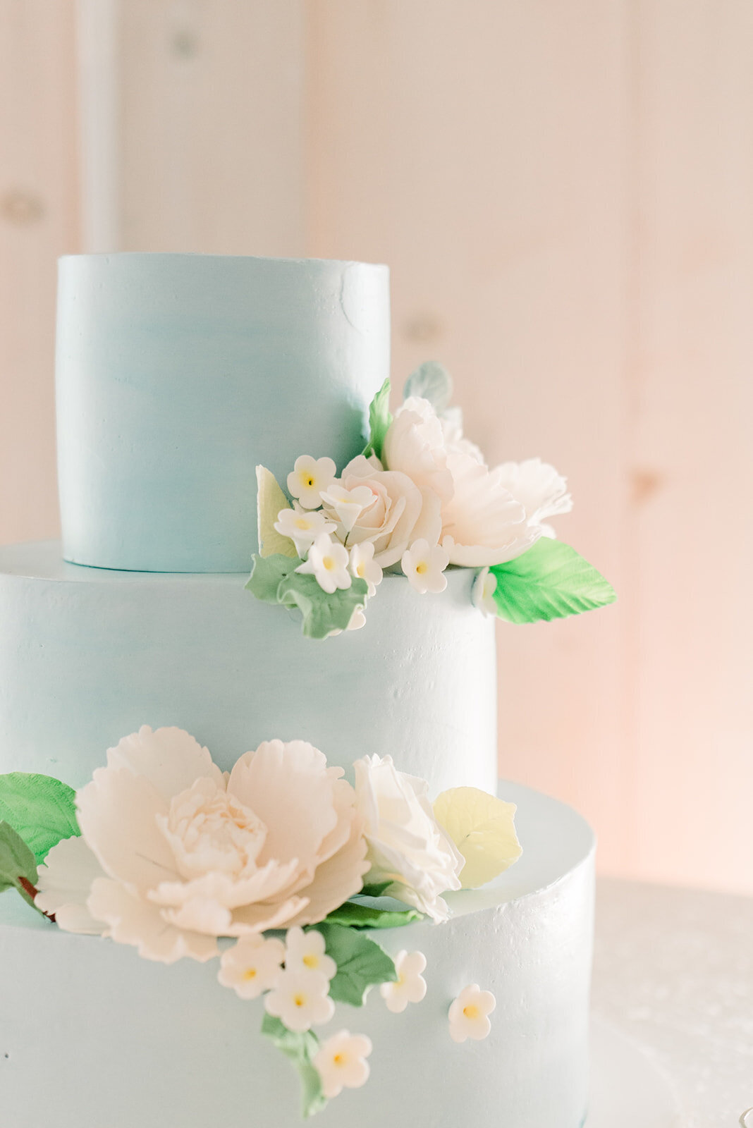 Details of a blue three tier cake with white flowers