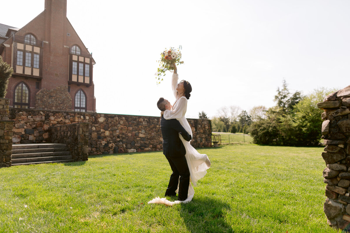 Couple twirling in the grass behind a manor house