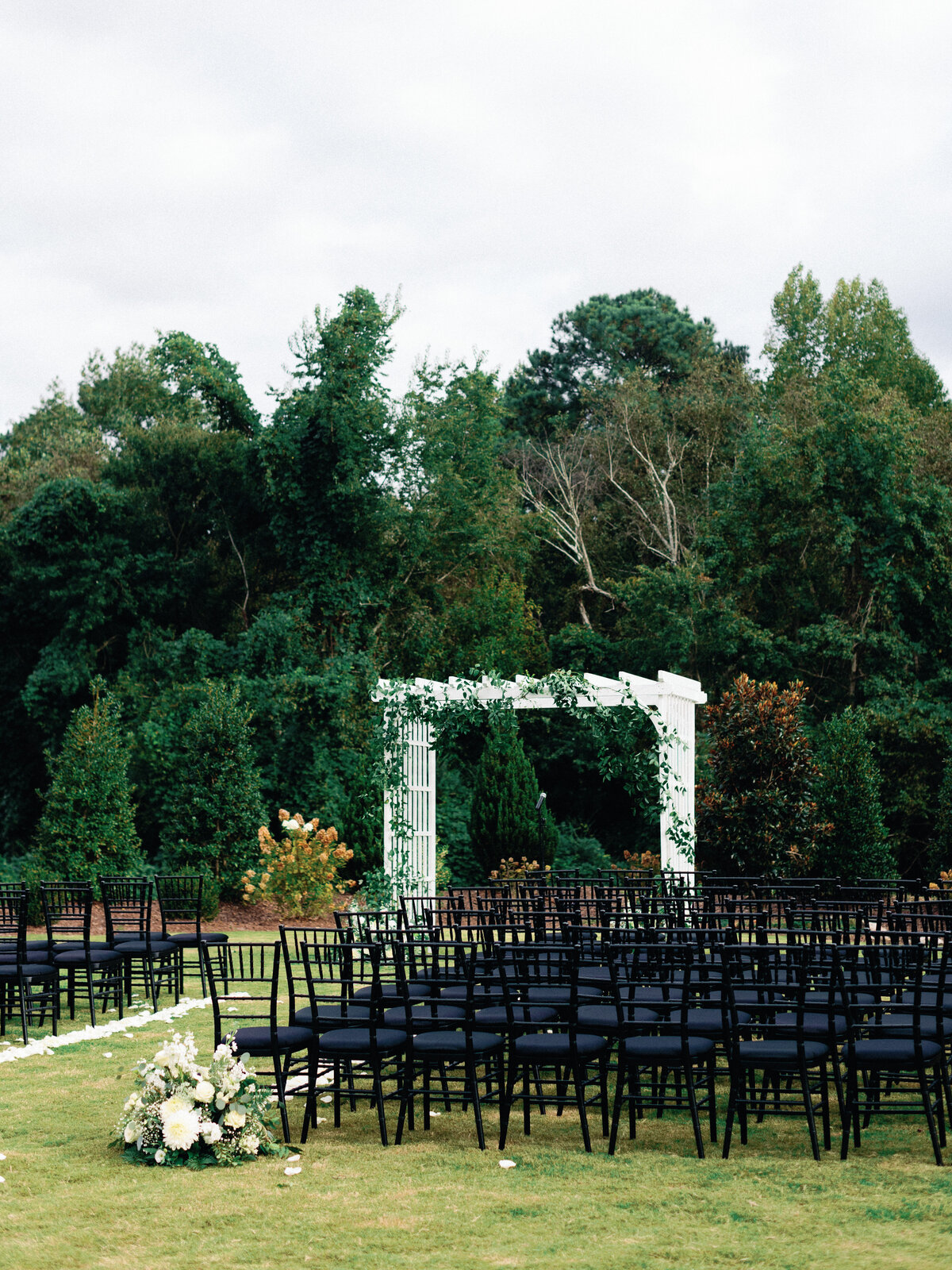 Black chairs with white garden ceremony arbor