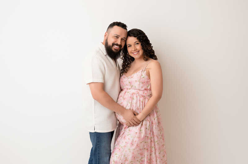 Pregnant woman in lace dress standing with her partner during Houston maternity photoshoot