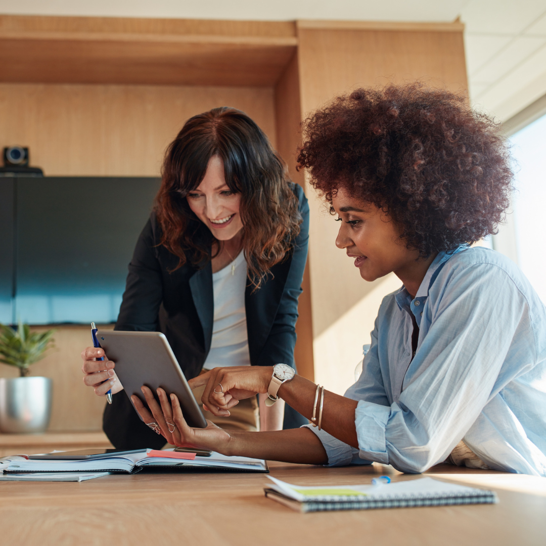two women smiling, working in a conference room