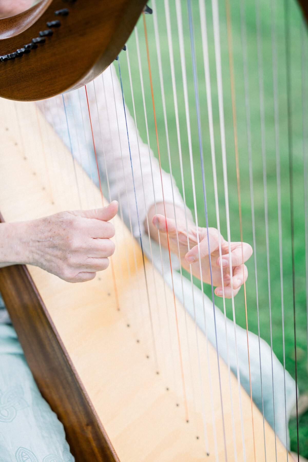 up close detail shot of fingers playing the harp on the lawn of rosecliff mansion during ceremony 