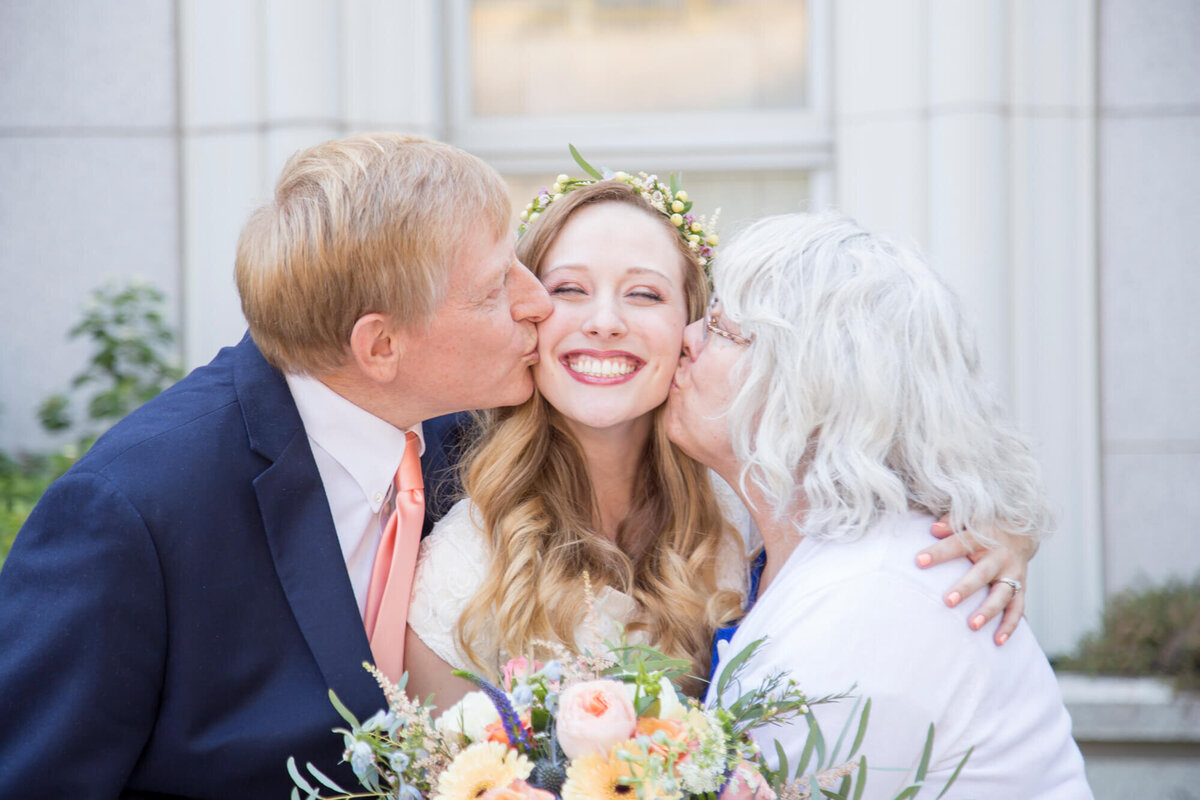 light and airy wedding photography of happy bride kissed on both cheeks by parents