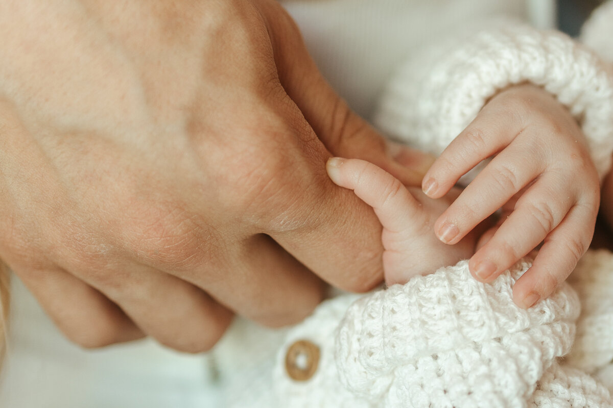 Dad holding newborn baby girls fingers during in home newborn session with Alexis Adkins Photography in Firestone Colorado