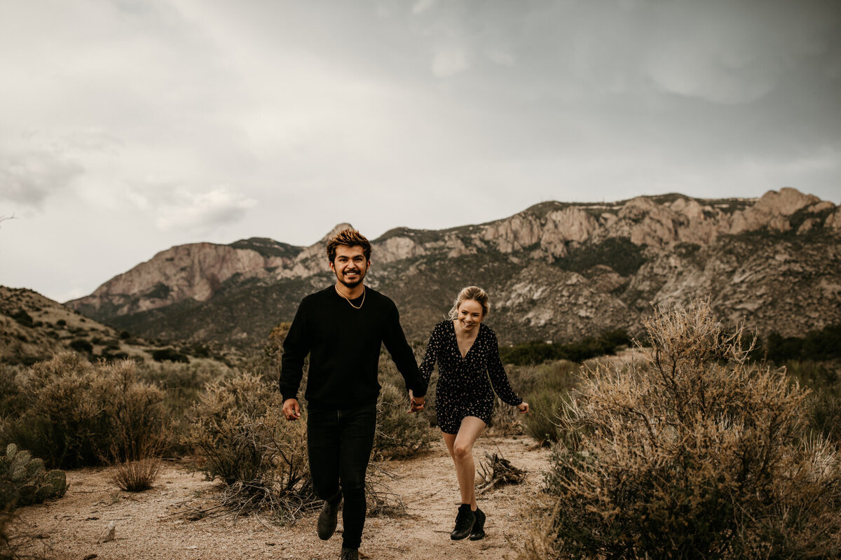 engaged couple running in the desert