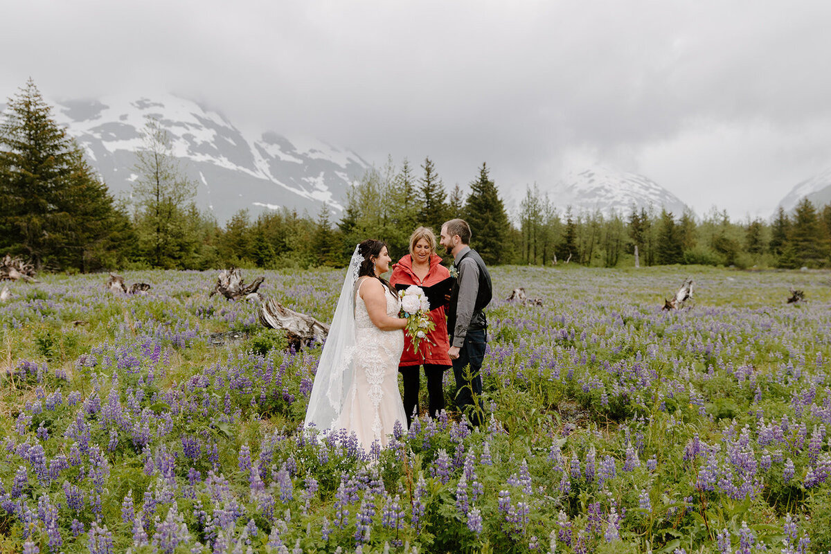Elopement couple recites their wedding vows in a lupine field.