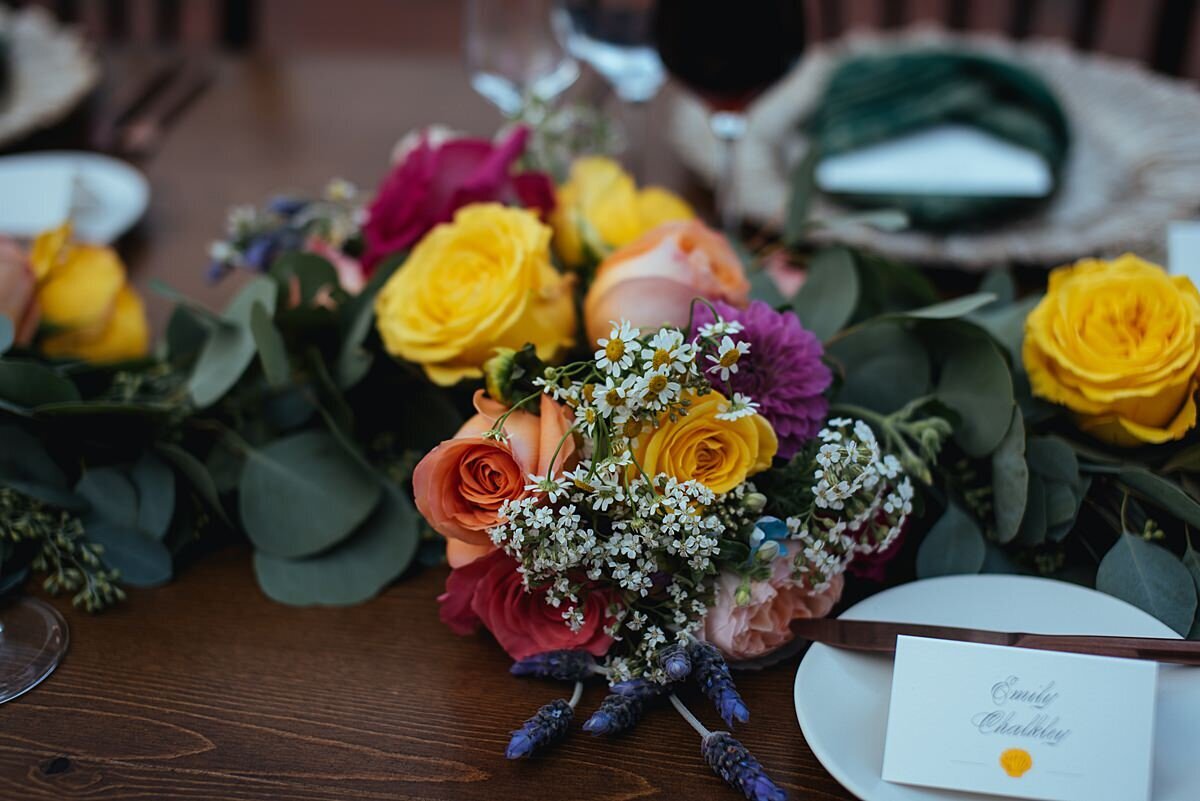 orange, yellow, ivory and hot pink floral centerpiece on a dark wood farm table at Cheekwood
