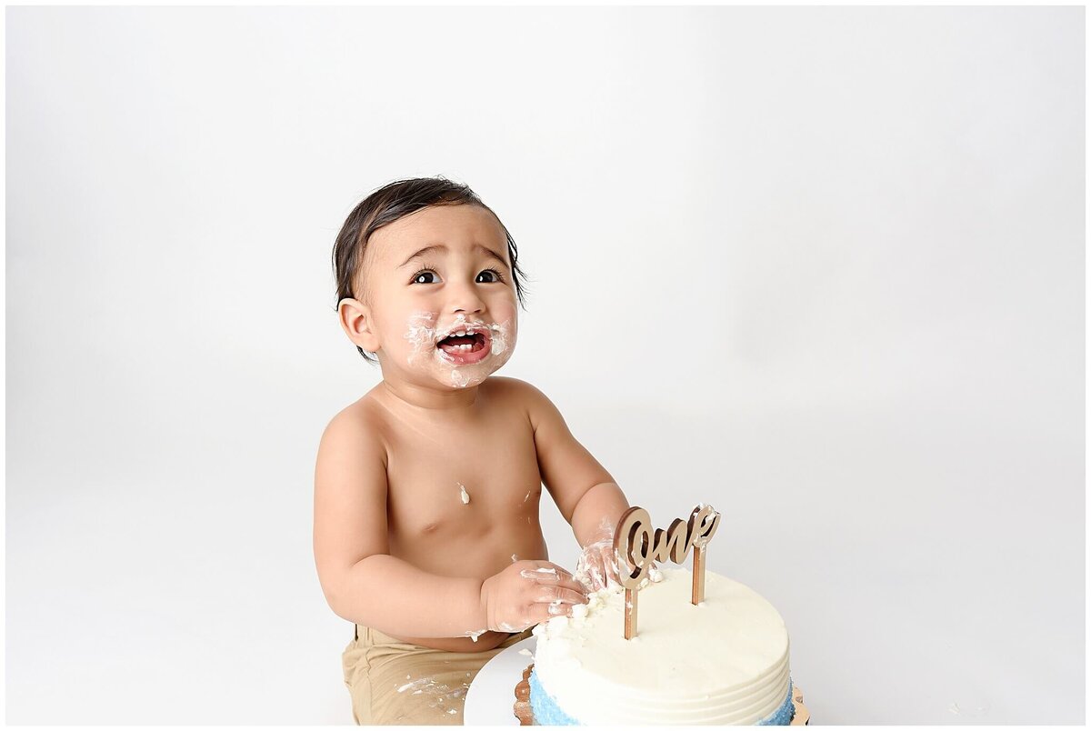 Cake smash session with little boy touching cake.