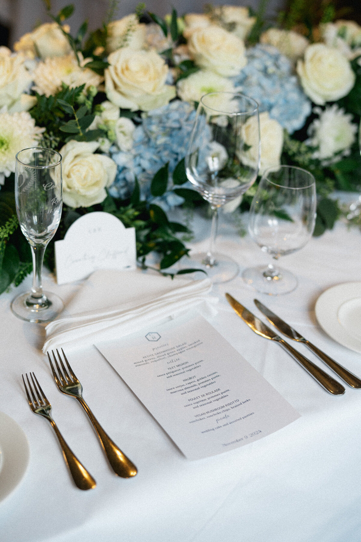 Blue and white floral centerpiece with wedding menu and place setting