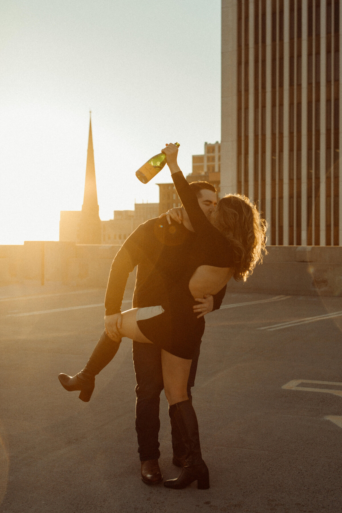 Couple pops a bottle of champagne at a Buffalo rooftop engagement