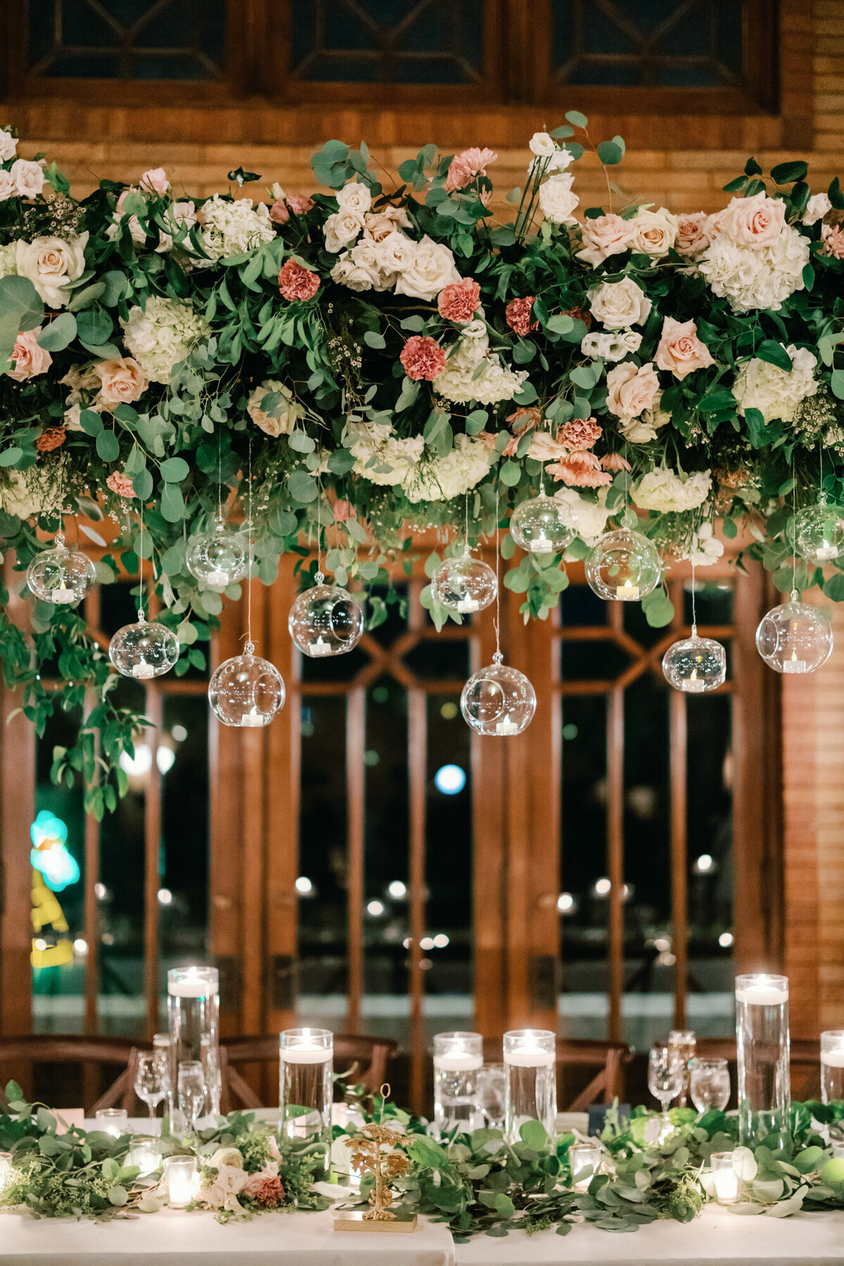 A breathtaking floral installation suspended above the head table at a Café Brauer wedding, featuring lush greenery and elegant blooms.