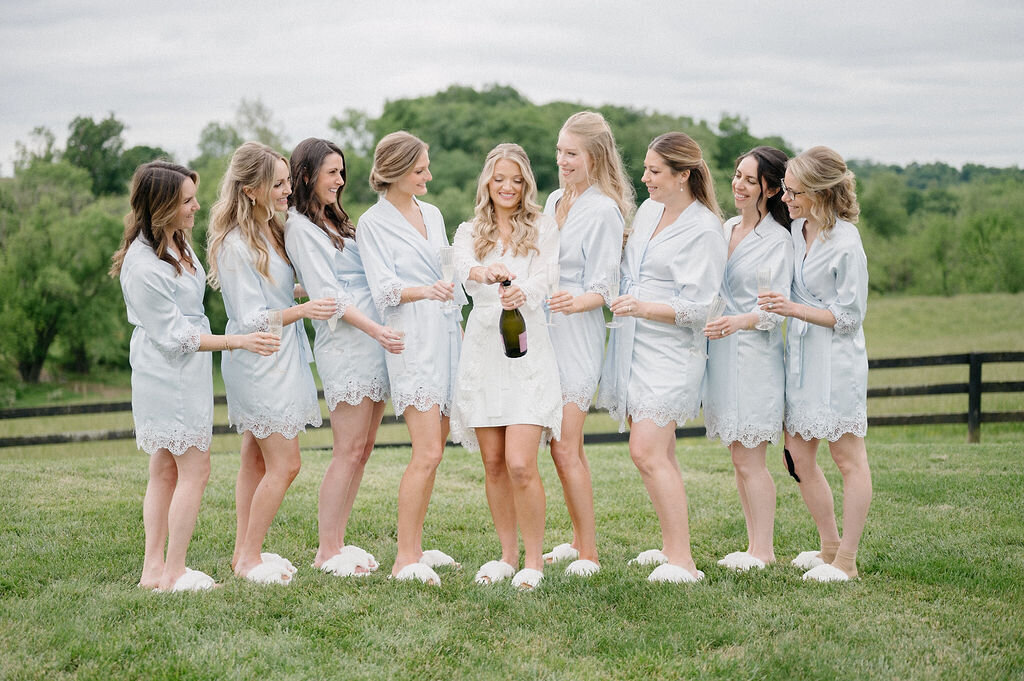 Bride opening a bottle and bridesmaids cheering her