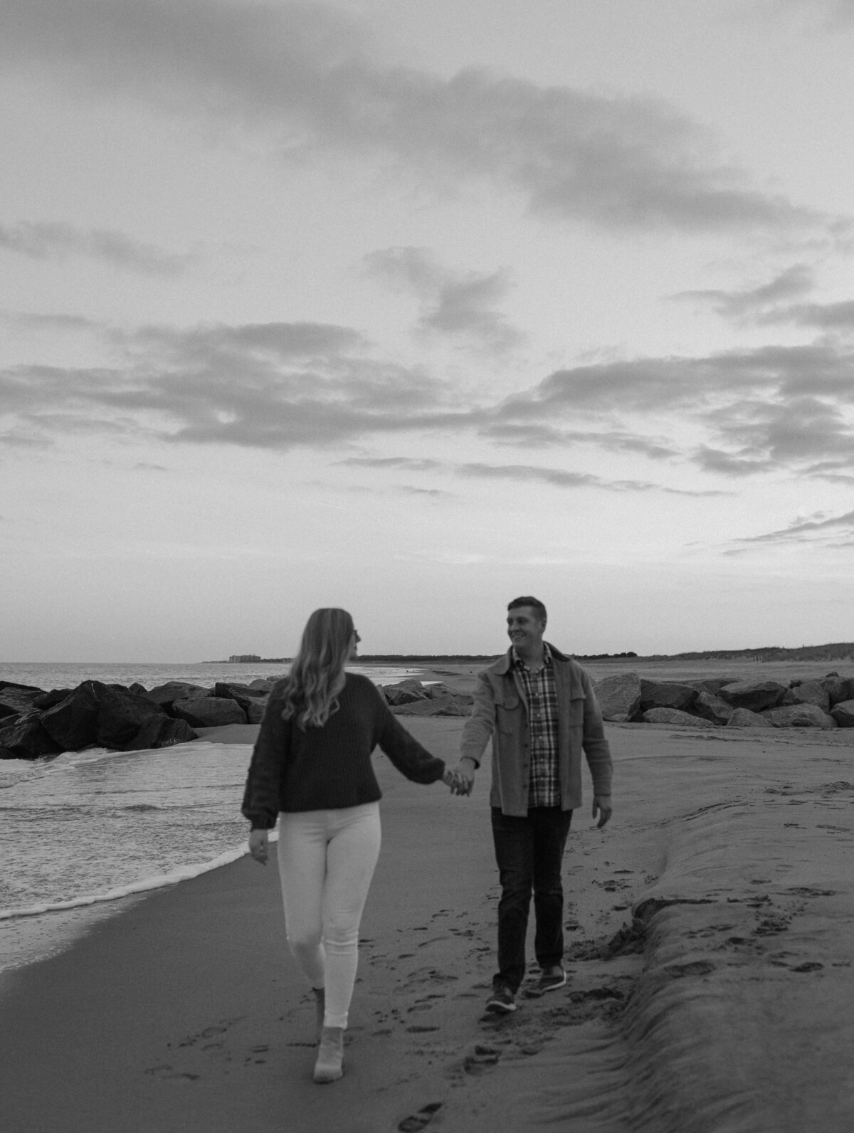 dreamy couple photograph walking down beach during winter sunset in lewes beach delaware
