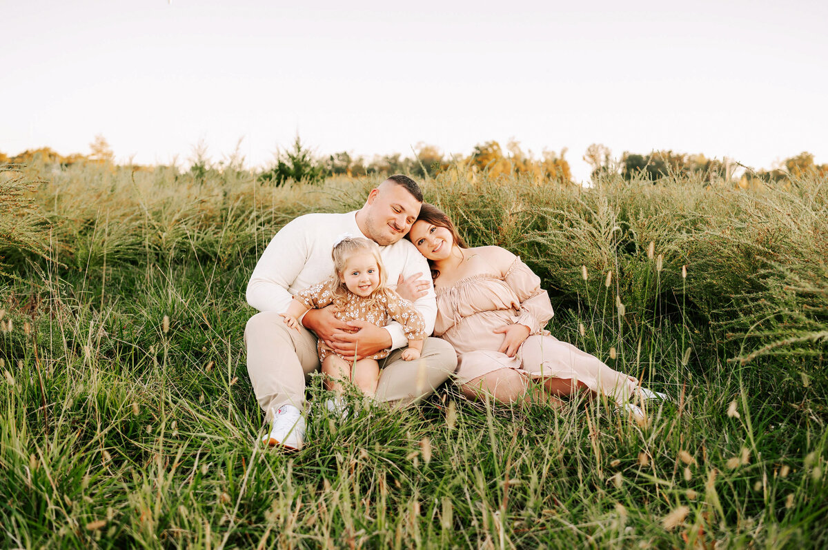 pregnant couple cuddling at sunset in a field during Joplin Mo maternity photography session